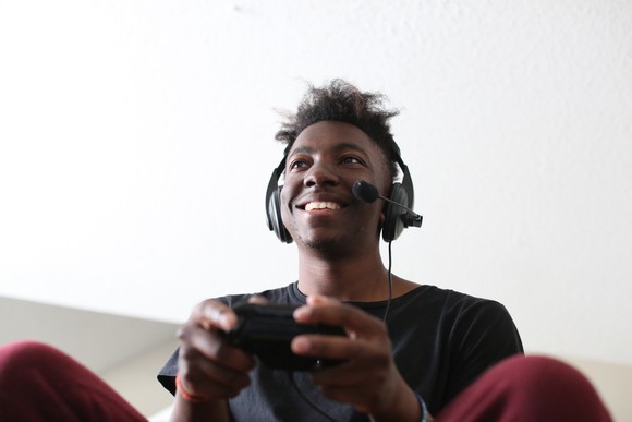 A young man wearing a headset and holding a console controller