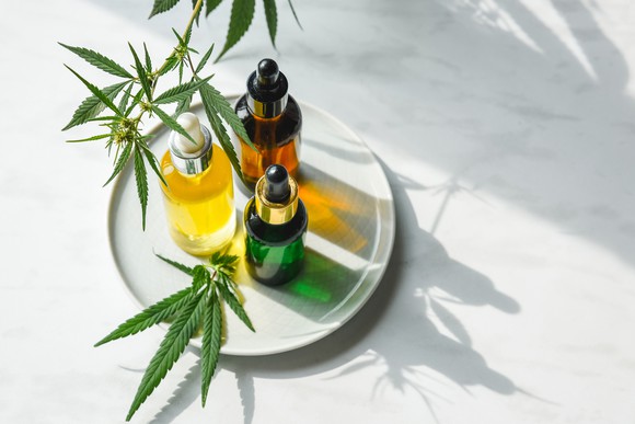 Glass bottles with CBD oil, THC tincture and hemp leaves