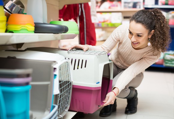 A woman picks out a small animal carrier in a pet store.