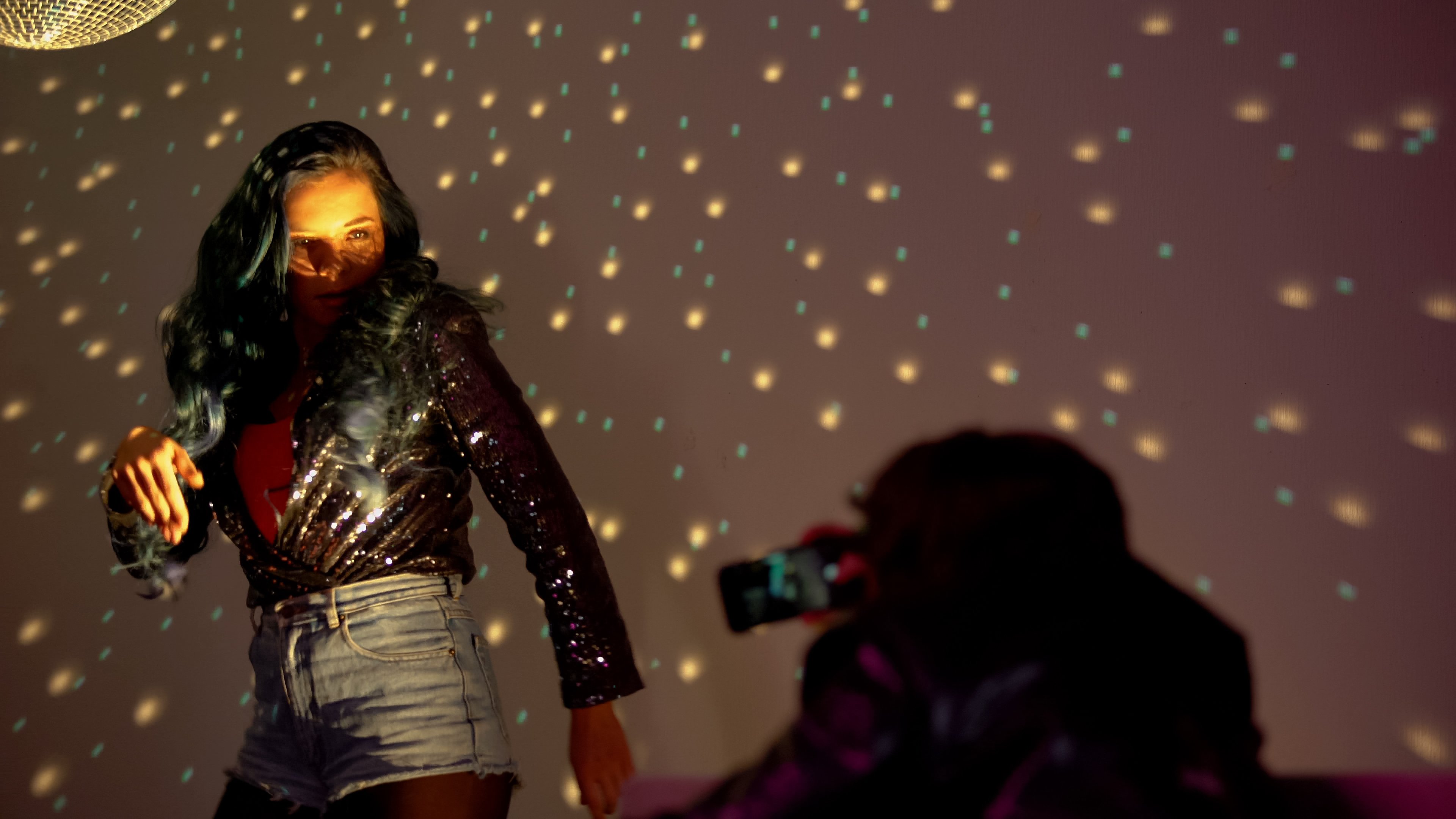 A woman dances while being filmed on a smartphone.