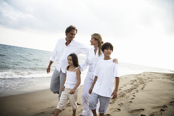 Family walking on a beach, parents and two kids.