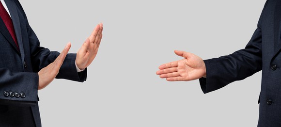 One businessman declines a handshake being offered by another businessman.