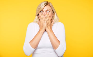 A surprised woman covers her mouth with her hands