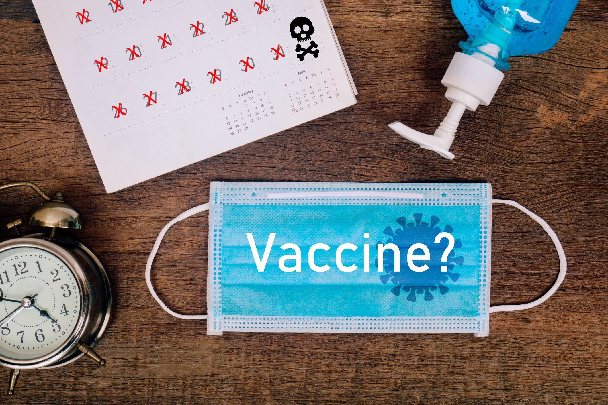 "Vaccine?" printed on a mask next to a clock, calendar, and hand sanitizer bottle. 