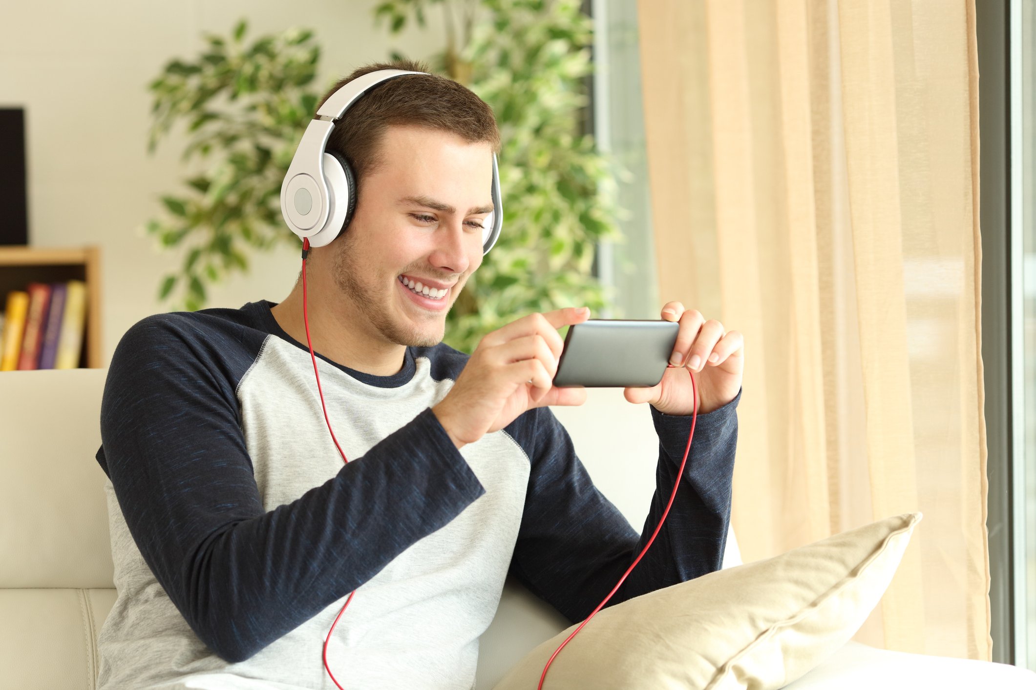 Young man listening to headphones plugged into a smartphone