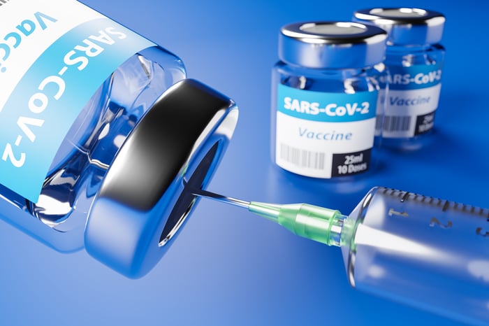 A syringe fills from a vial labeled as SARS-CoV2 Vaccine.