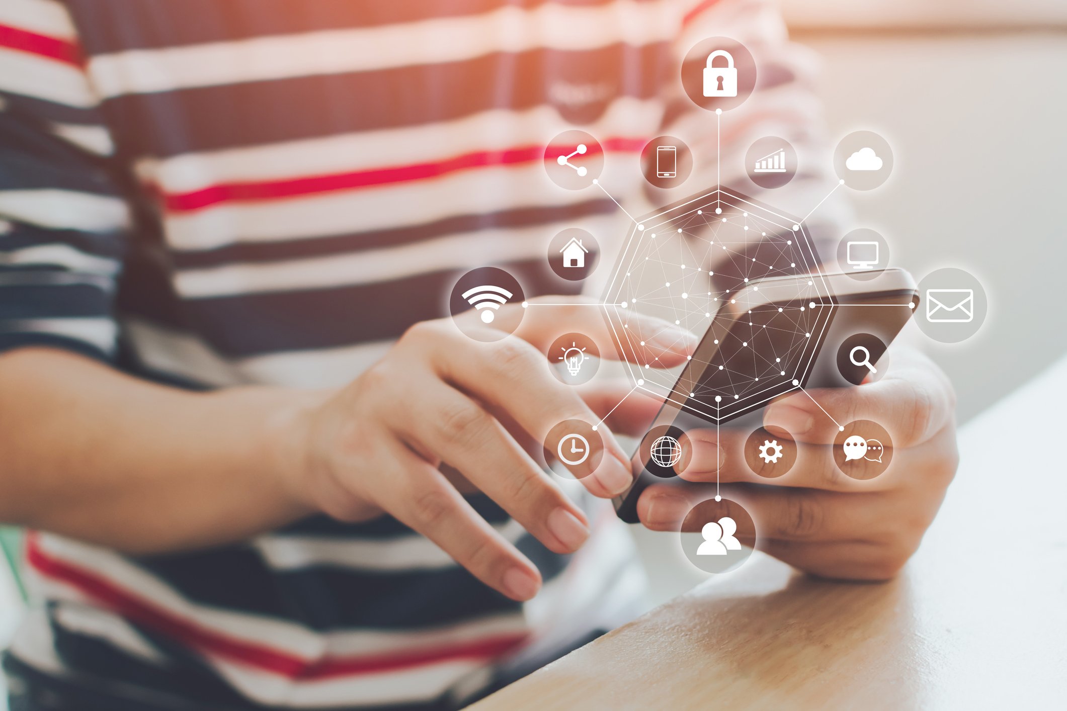 A person uses a smartphone with digital icons surrounding it.