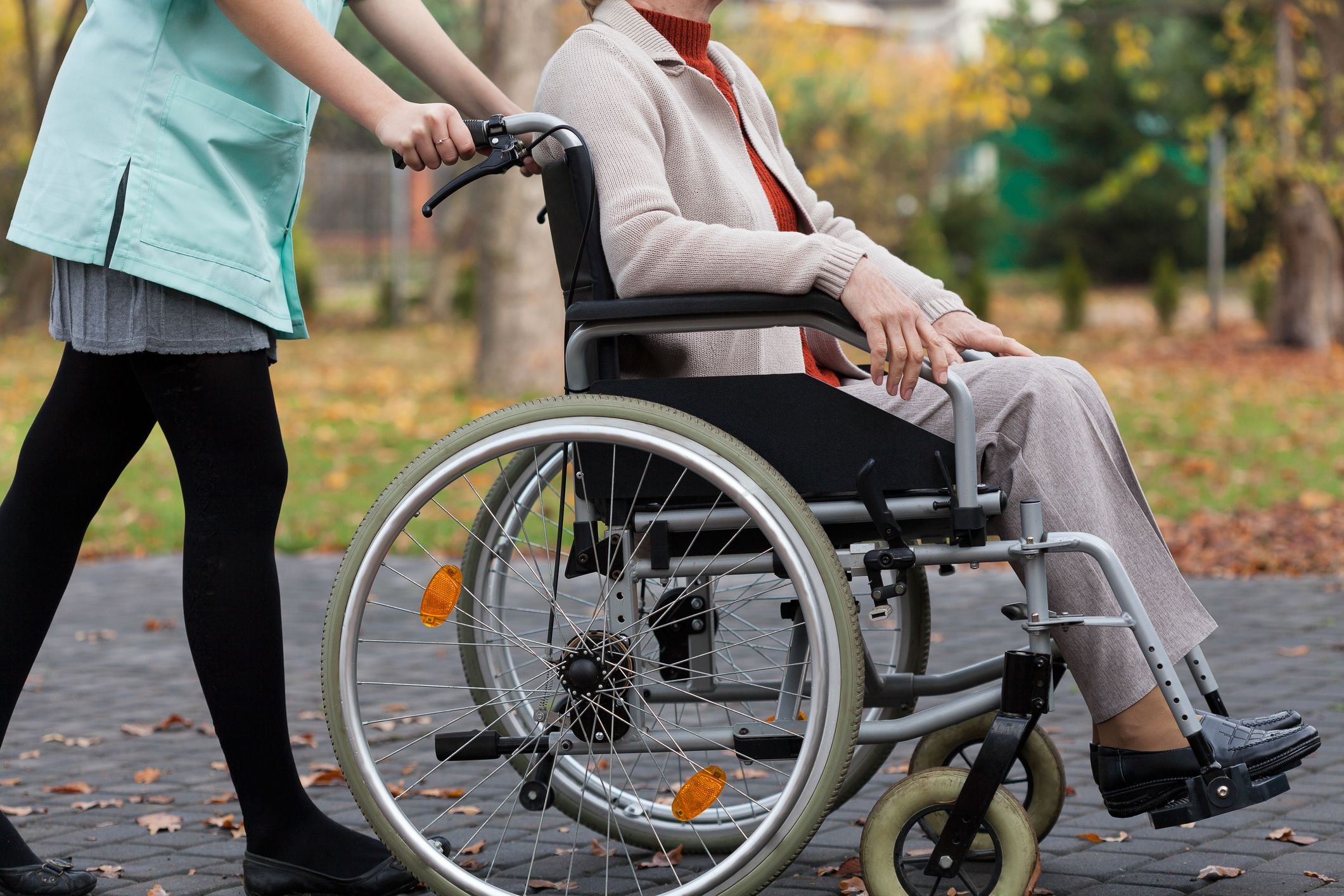 Older woman being pushed in a wheelchair by a caregiver.
