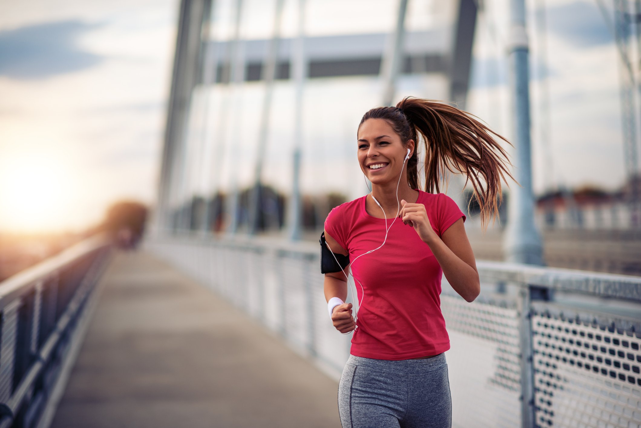 A woman jogging over a bridge.