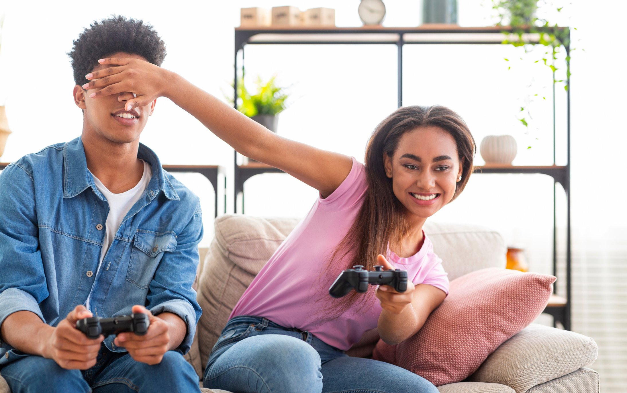 Teenage couple sitting on a couch playing a video game.
