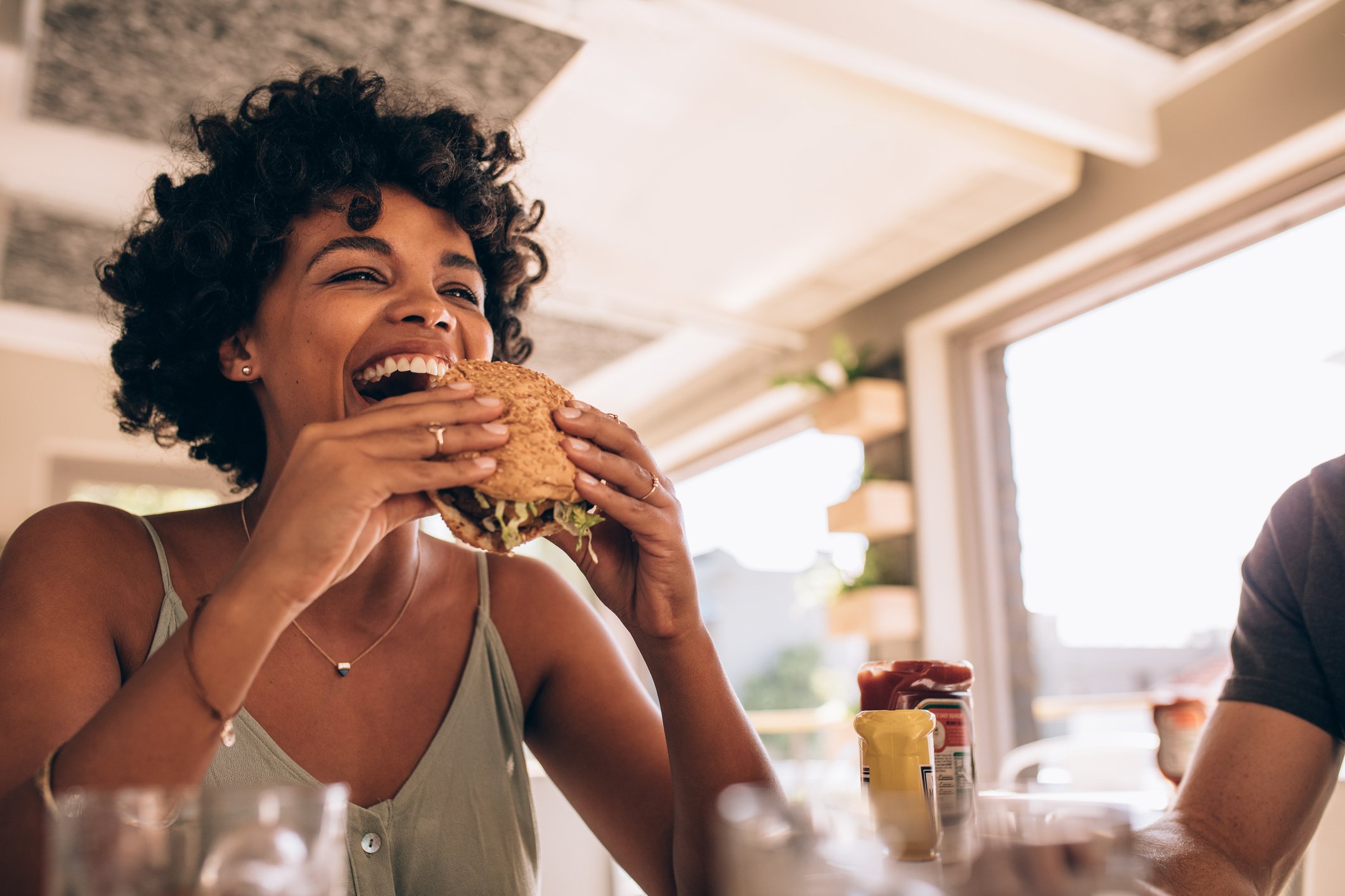 A woman bites into a veggie burger at a restaurant.