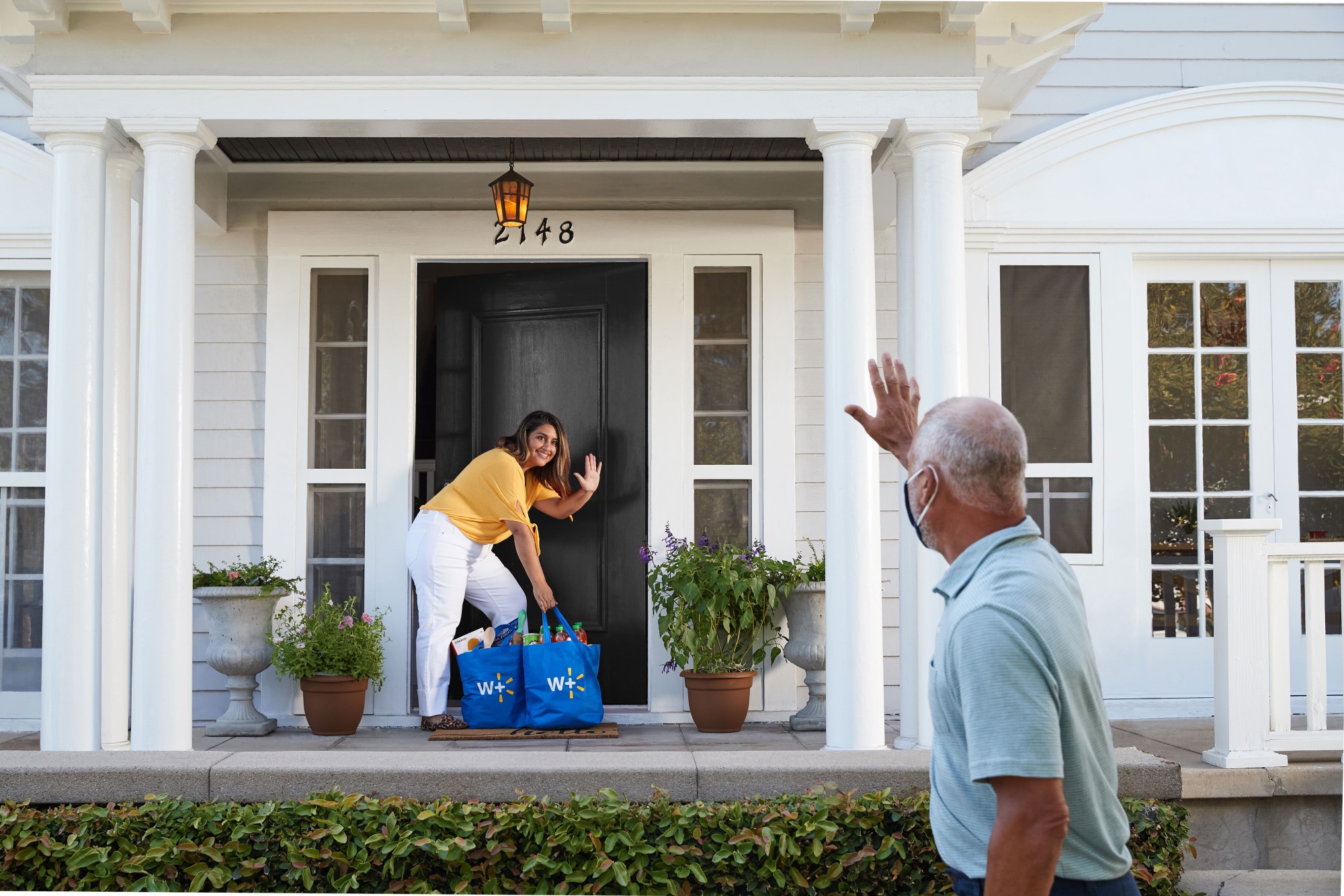 A man waving to a woman with Walmart bags.