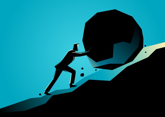 Businessman pushing a rock uphill