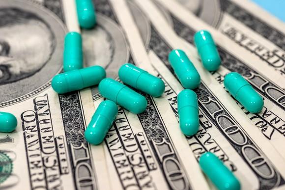 drug capsules on top of $100 bills