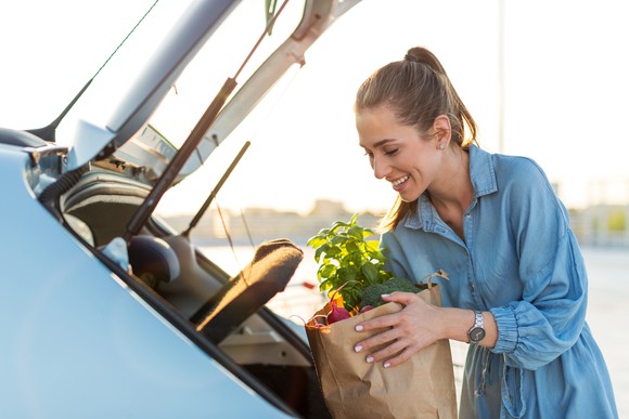 Woman putting groceries into her car trunk.