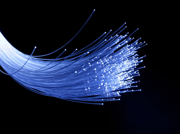 A handful of fiber-optic cables lit up against a black backdrop.