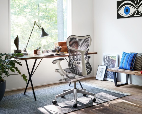 A Herman Miller "Mirra 2" chair faces a contemporary desk and window in a home office.