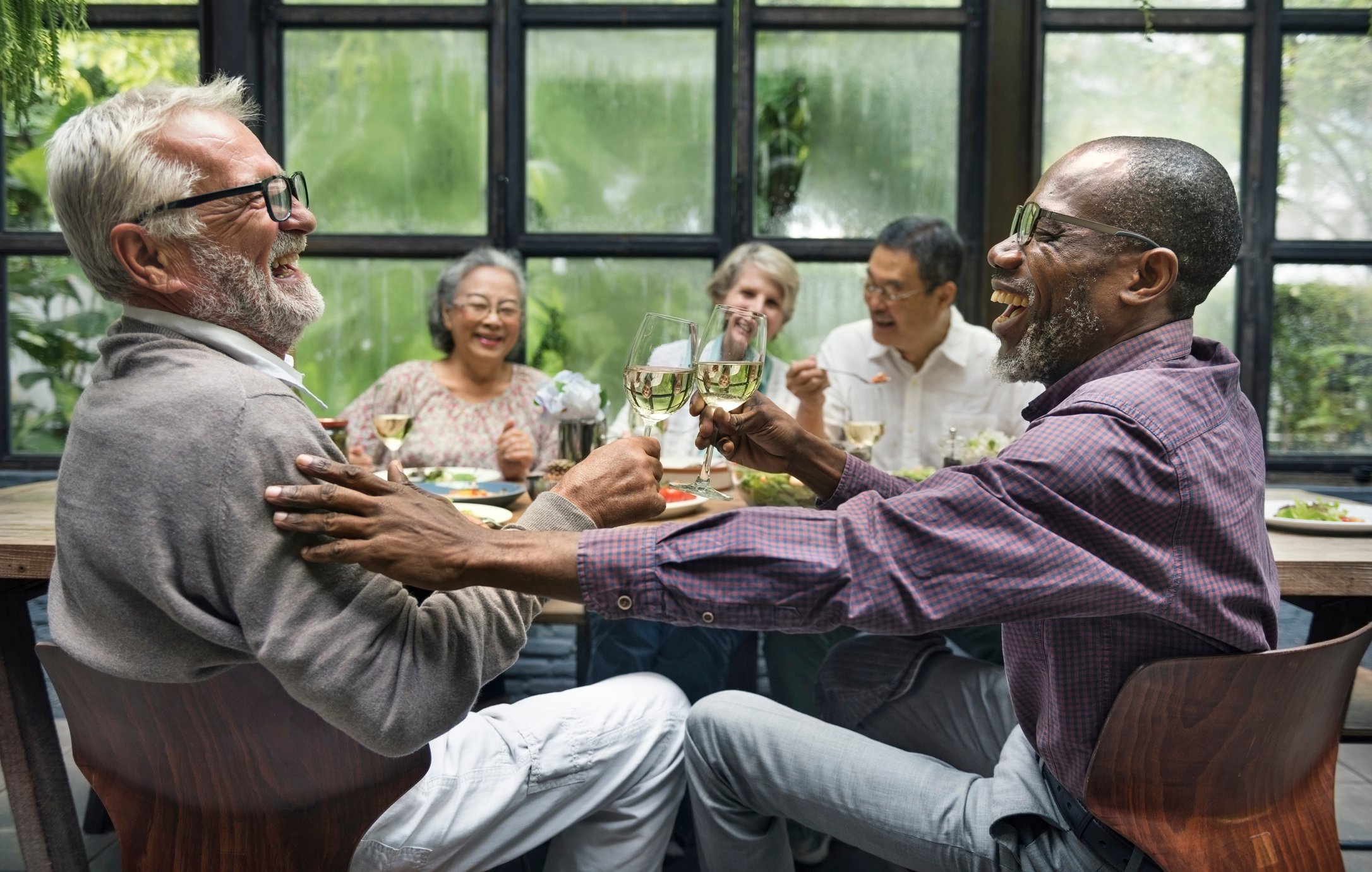 Five senior friends enjoying drinks at a dinner party.