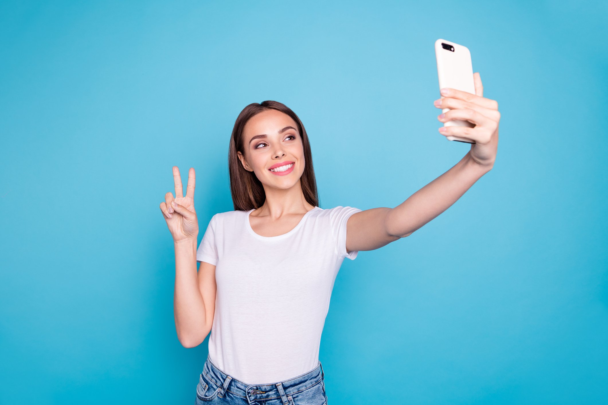 Woman giving peace sign while taking selfie