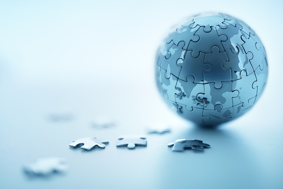 Jigsaw puzzle pieces next to a small globe formed by jigsaw puzzle pieces