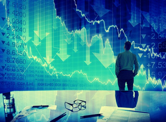 Man in front of board showing falling financial figures