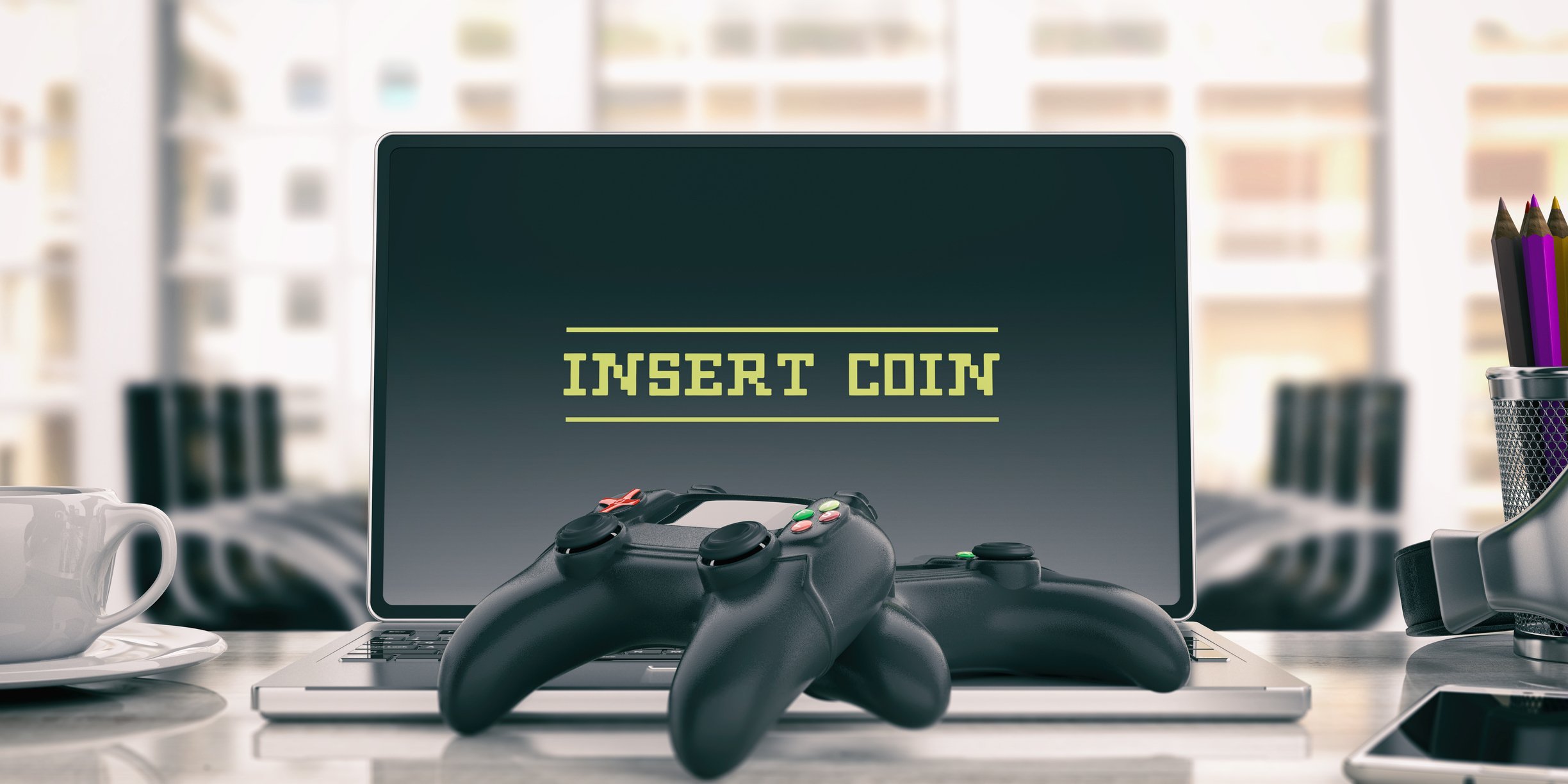 Two game controllers and a laptop with text 'Insert Coin.'