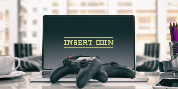 Two game controllers and a laptop with text 'Insert Coin.'
