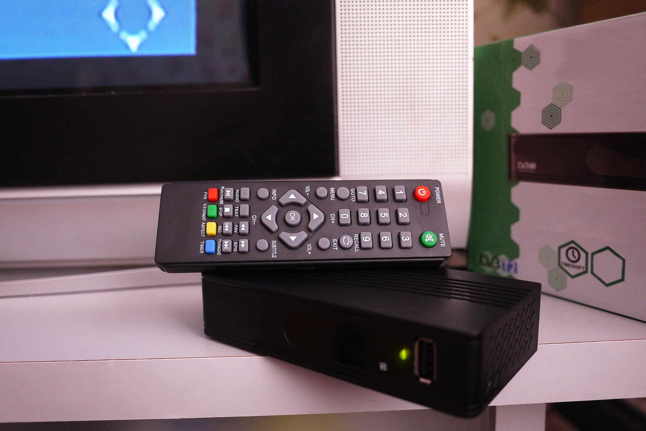 a cable remote and cable box on a TV stand next to a TV. 