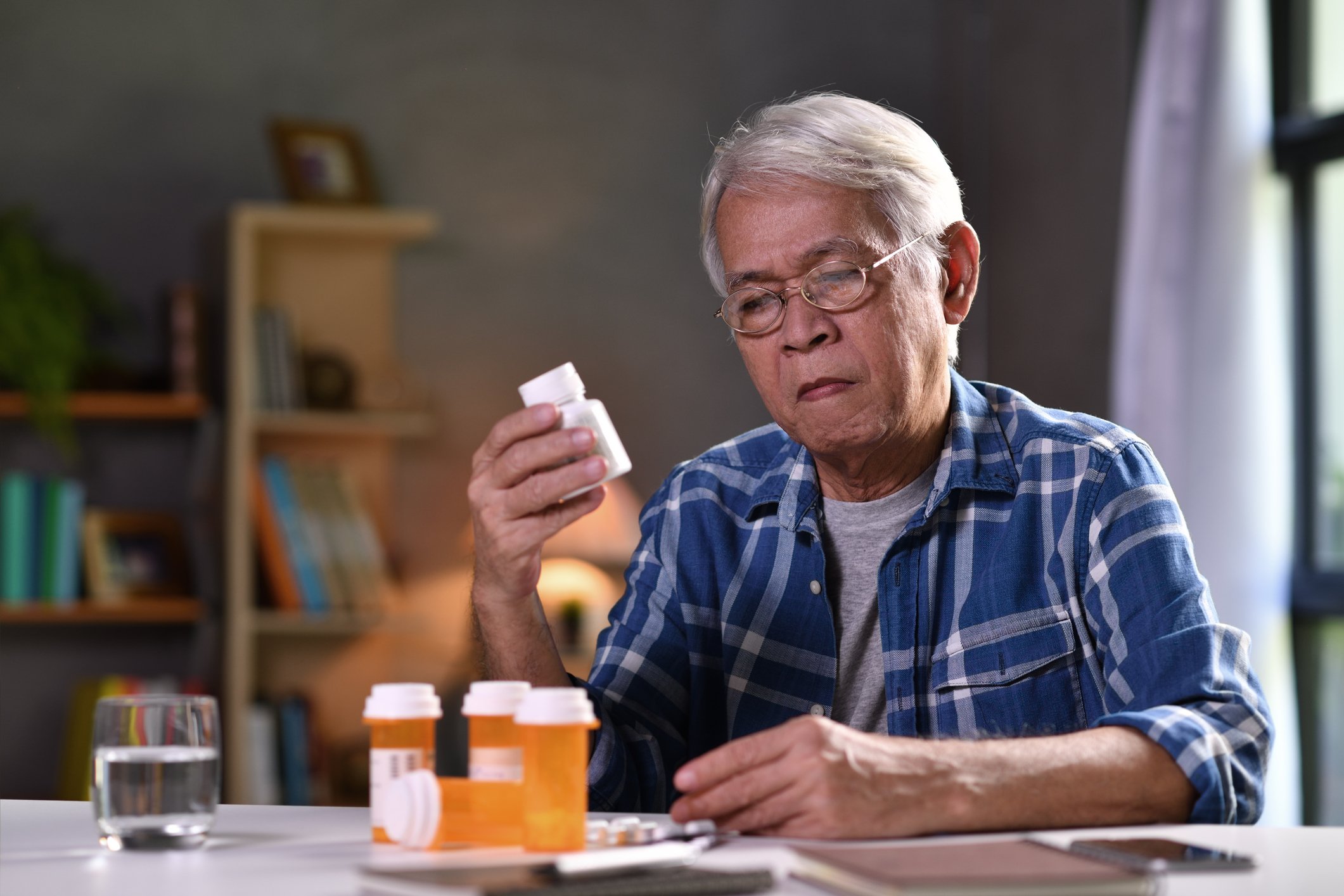 Elderly person at a table with bottles of pills.