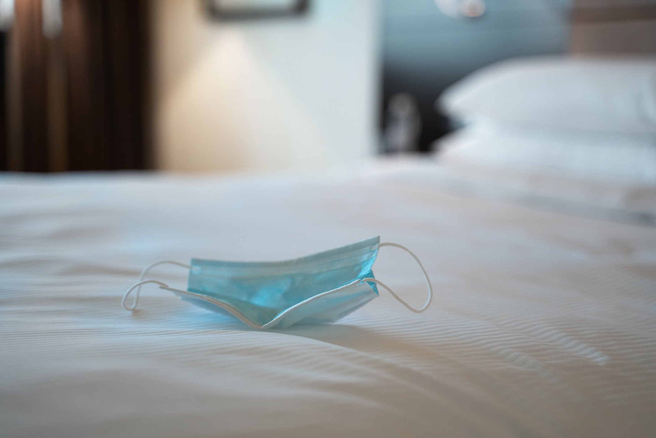 A bed with a disposable face mask on it.