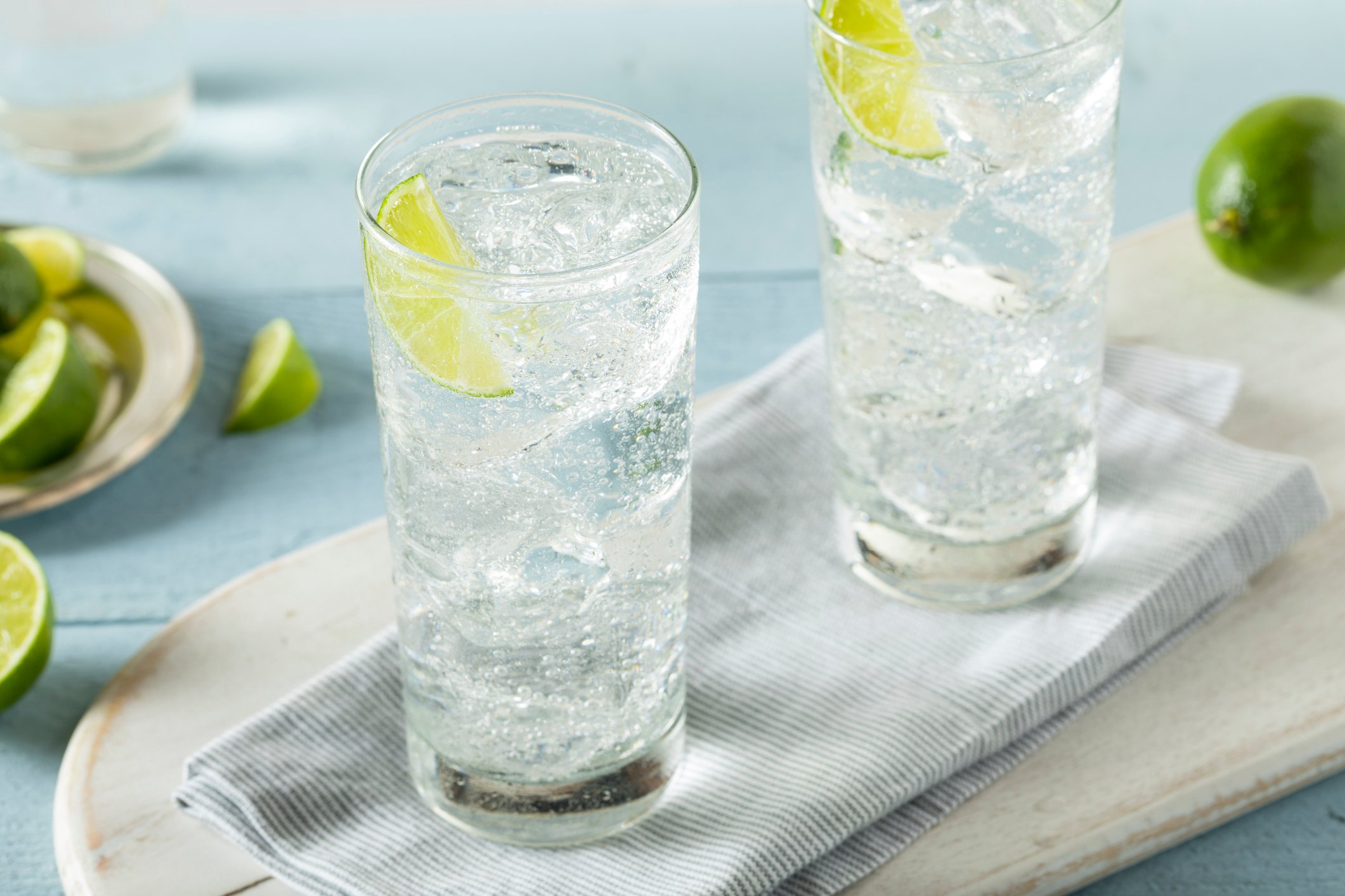 Two glasses of hard seltzer with ice cubes and slices of lime.