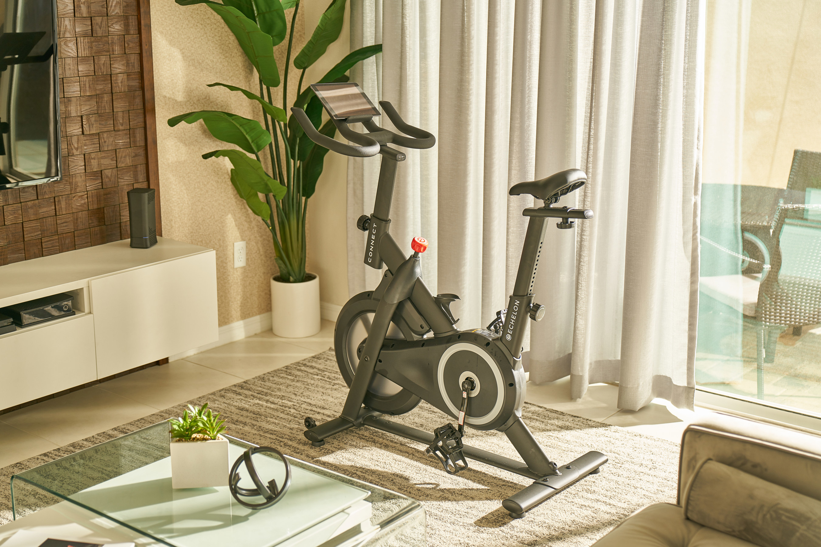 The Prime Bike in a furnished room with a sliding glass door and curtains behind it