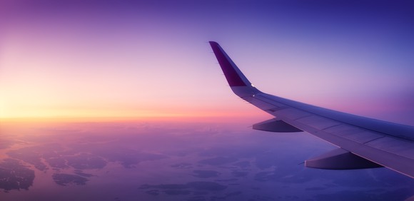 An airplane's wing gliding over a sunrise sky. 