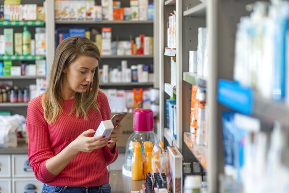 A woman looks at a box at a pharmacy.
