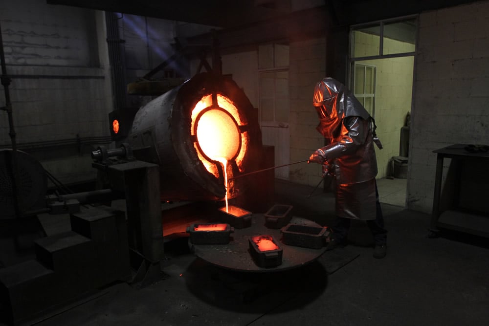 worker pouring molten silver out of a ladle 