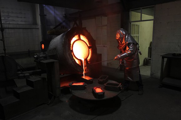 worker pouring molten silver out of a ladle 