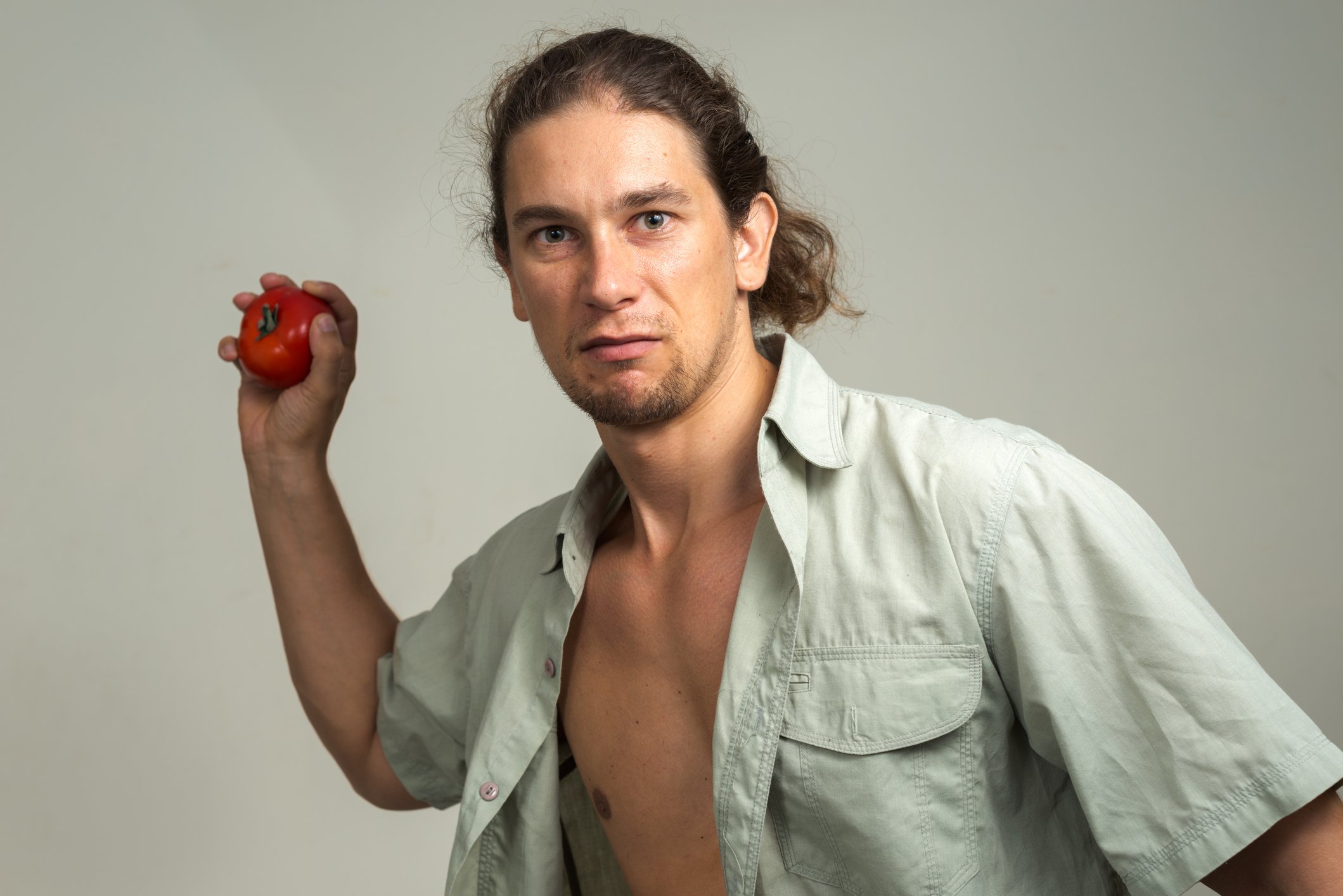 A man cocks his arm to throw a tomato.