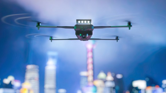 A drone in flight, with a city in the background.