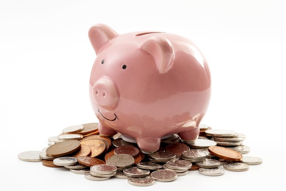 A smiling piggy bank sits on a pile of change.