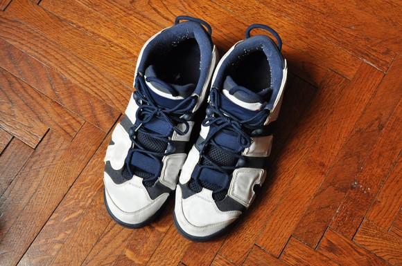 A pair of blue and white basketball shoes on a herringbone wood floor.