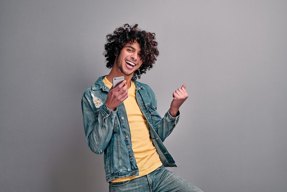 Smiling man dancing with smartphone