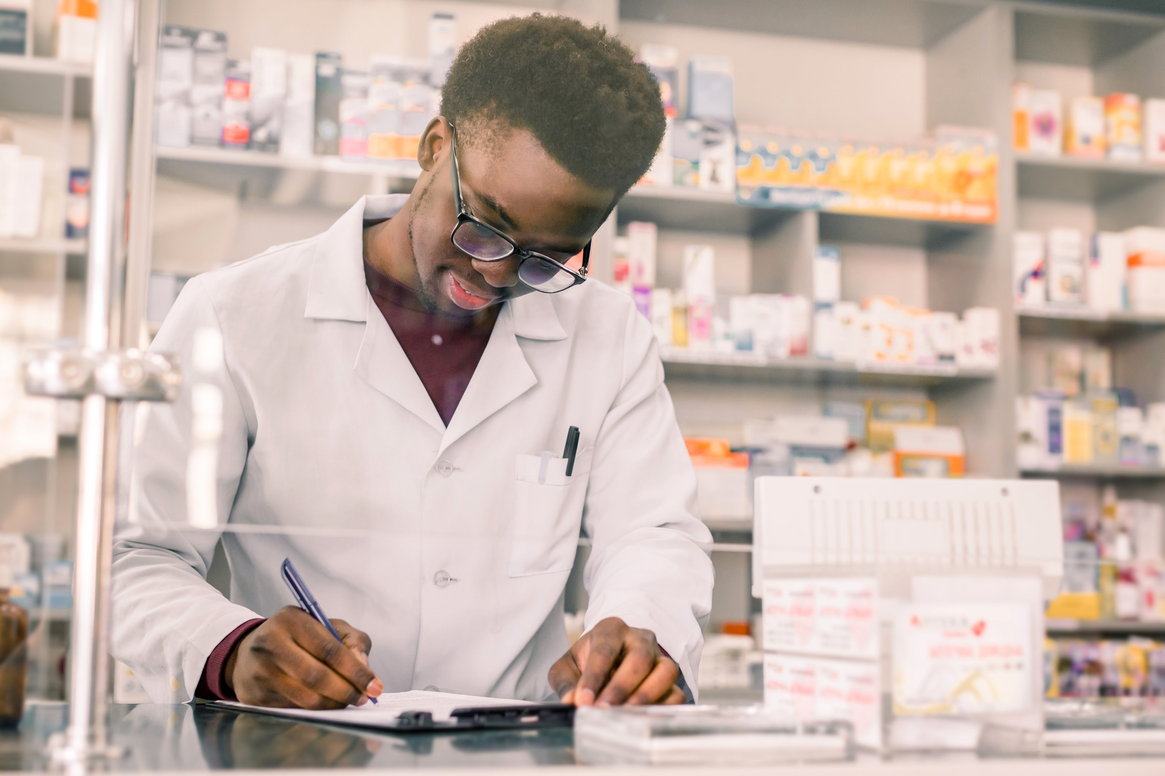 A pharmacist looks happy as he fills out a form