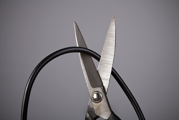 Pair of scissors cutting a coaxial cable TV cord