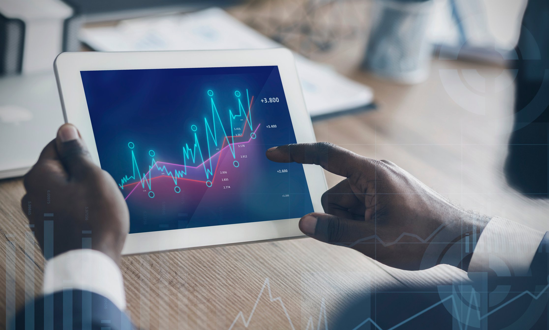 Man holding a tablet displaying rising charts.