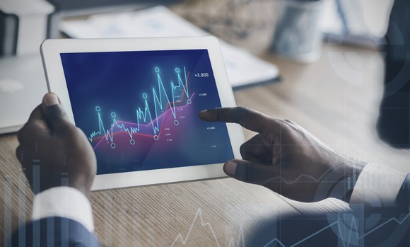 Man holding a tablet displaying rising charts.