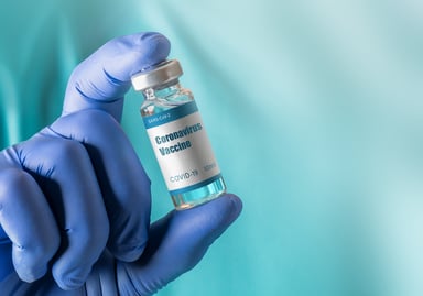 Gloved hand holding coronavirus vaccine bottle