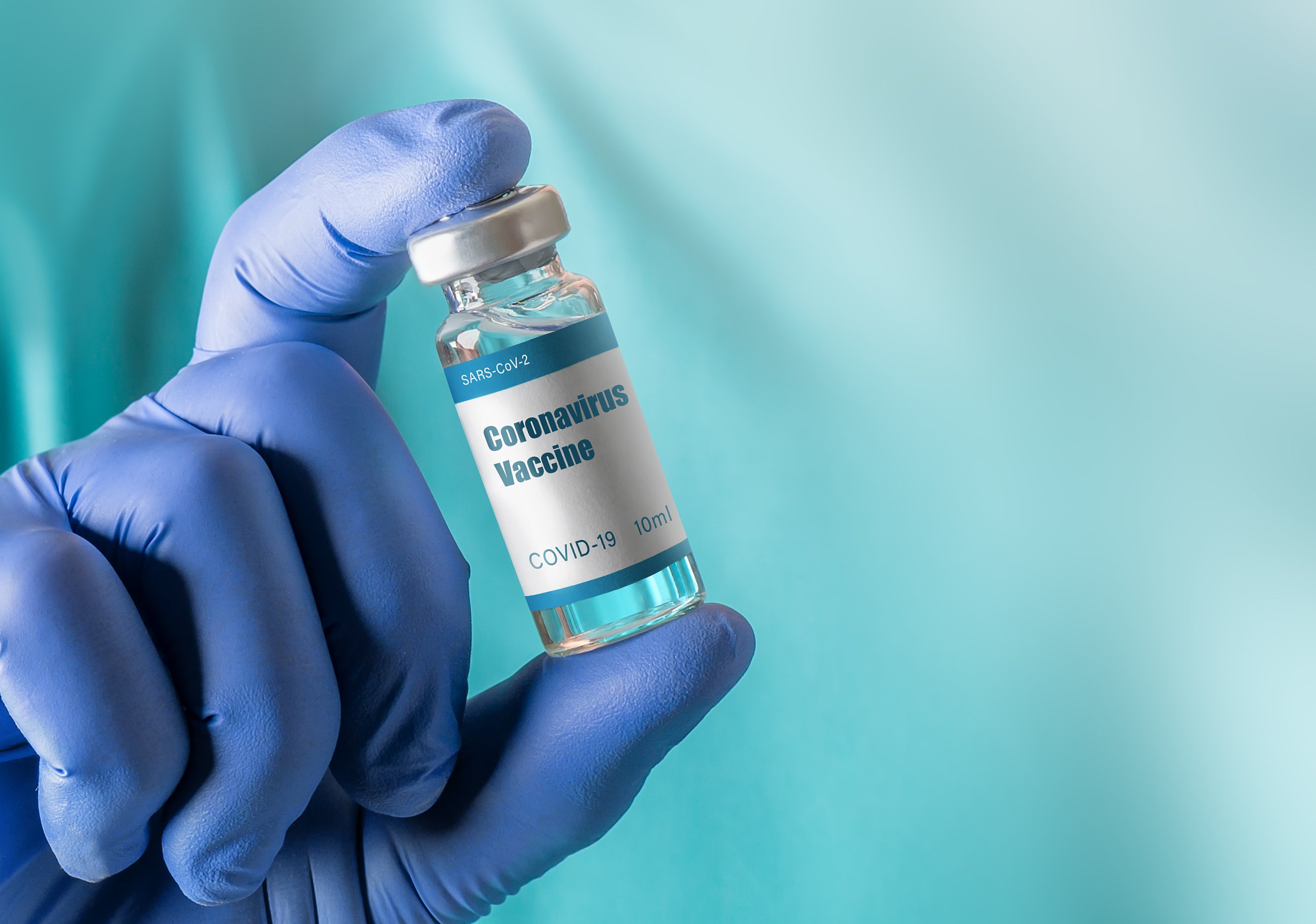 Gloved hand holding a coronavirus vaccine bottle