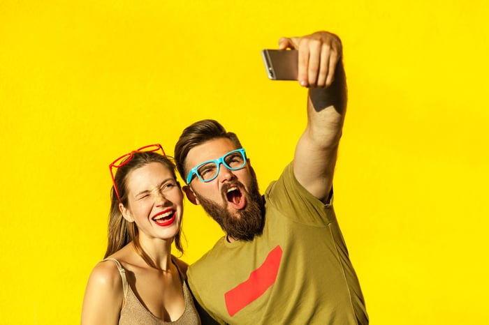 Couple mugging in front of a smartphone