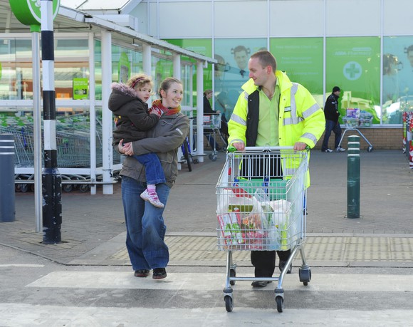 A customer and an Asda employee walk out of an Asda grocery store.