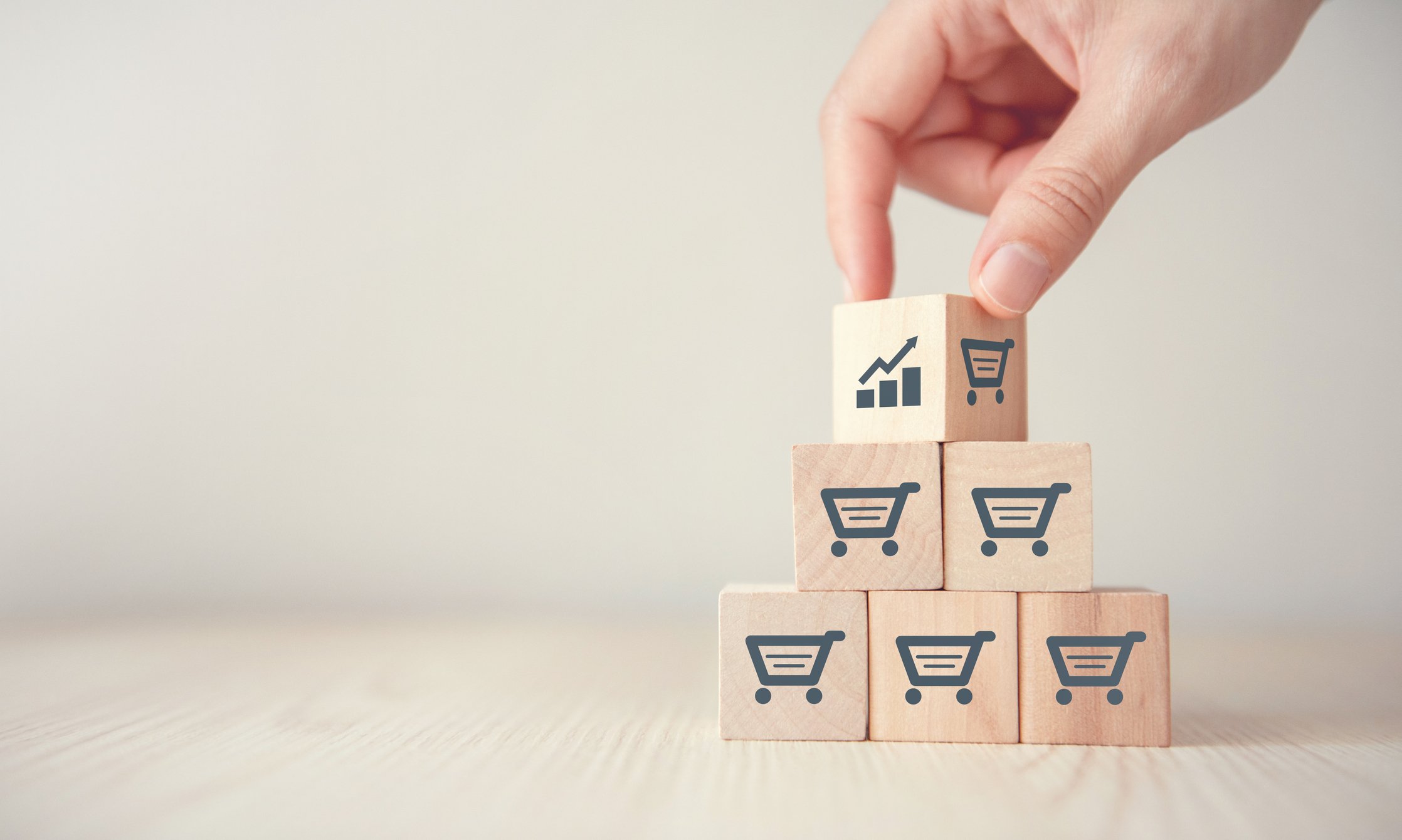 A person stacking blocks featuring shopping cart and chart icons.